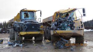 Two dump trucks, one with the windshield smashed, the other with the entire front end smashed.